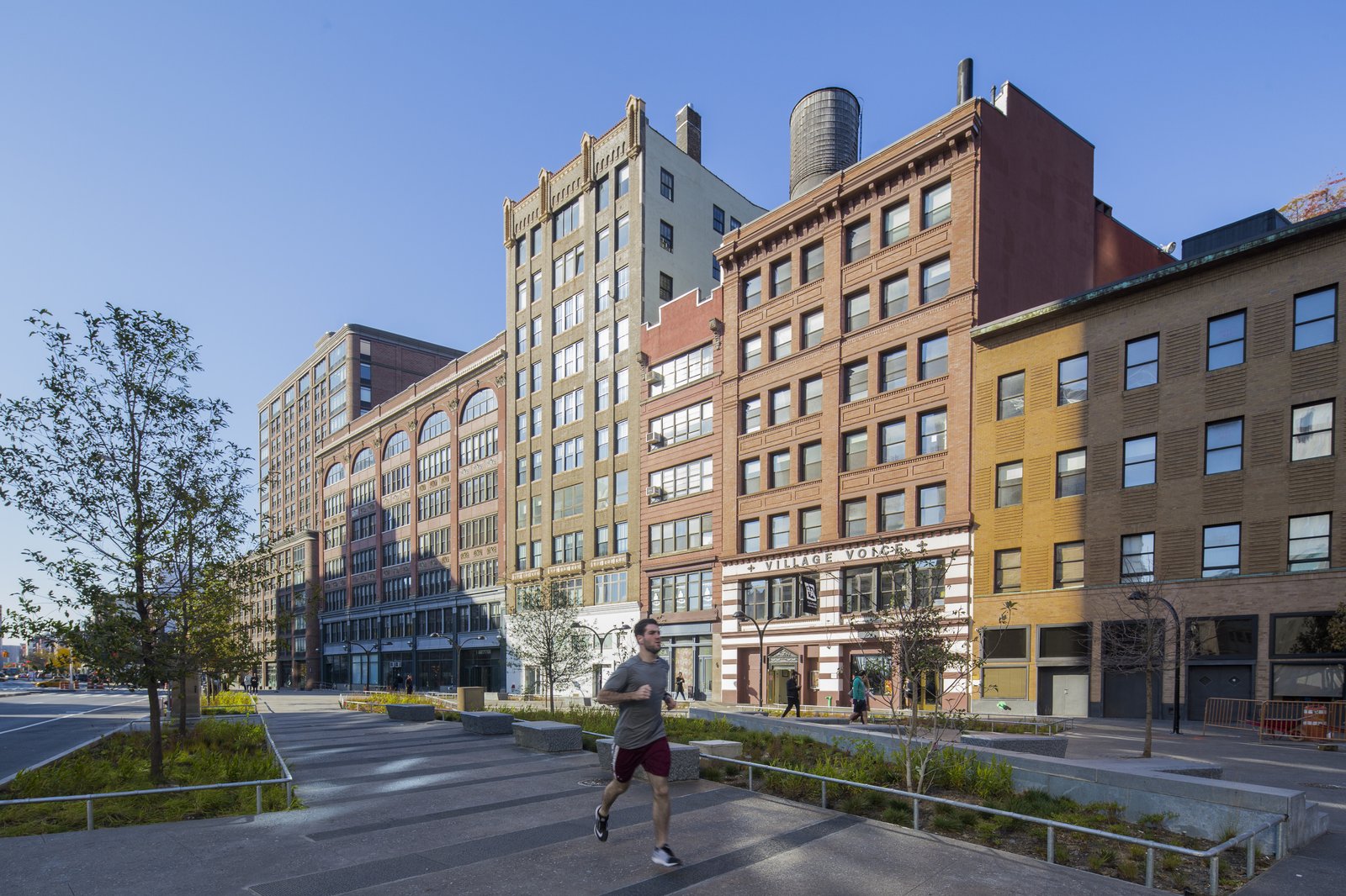 Runner passes by planters and historic buildings, with greenery and modern paving in the foreground.