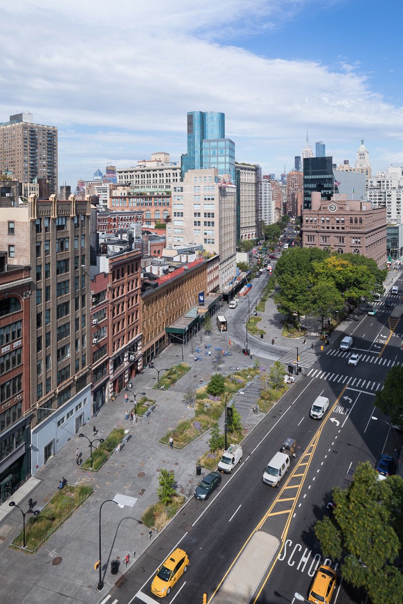 Aerial view of a reimagined urban corridor with landscaped plazas, historic buildings, and active streets.