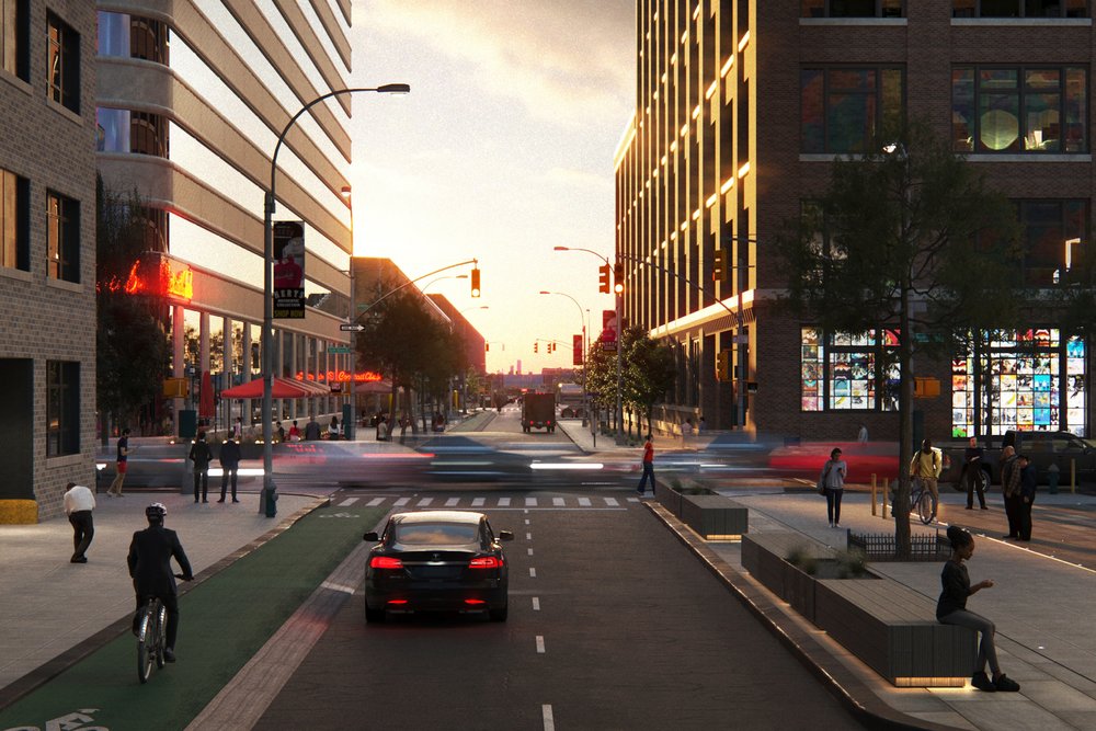 Urban street scene with cars, cyclists, and pedestrians at sunset.