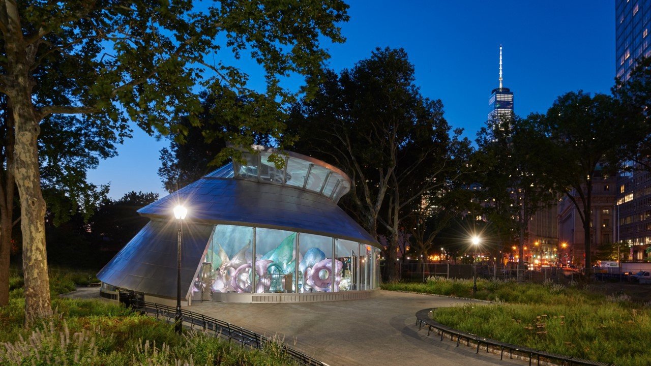 Illuminated carousel structure with fish sculptures at night in a park.