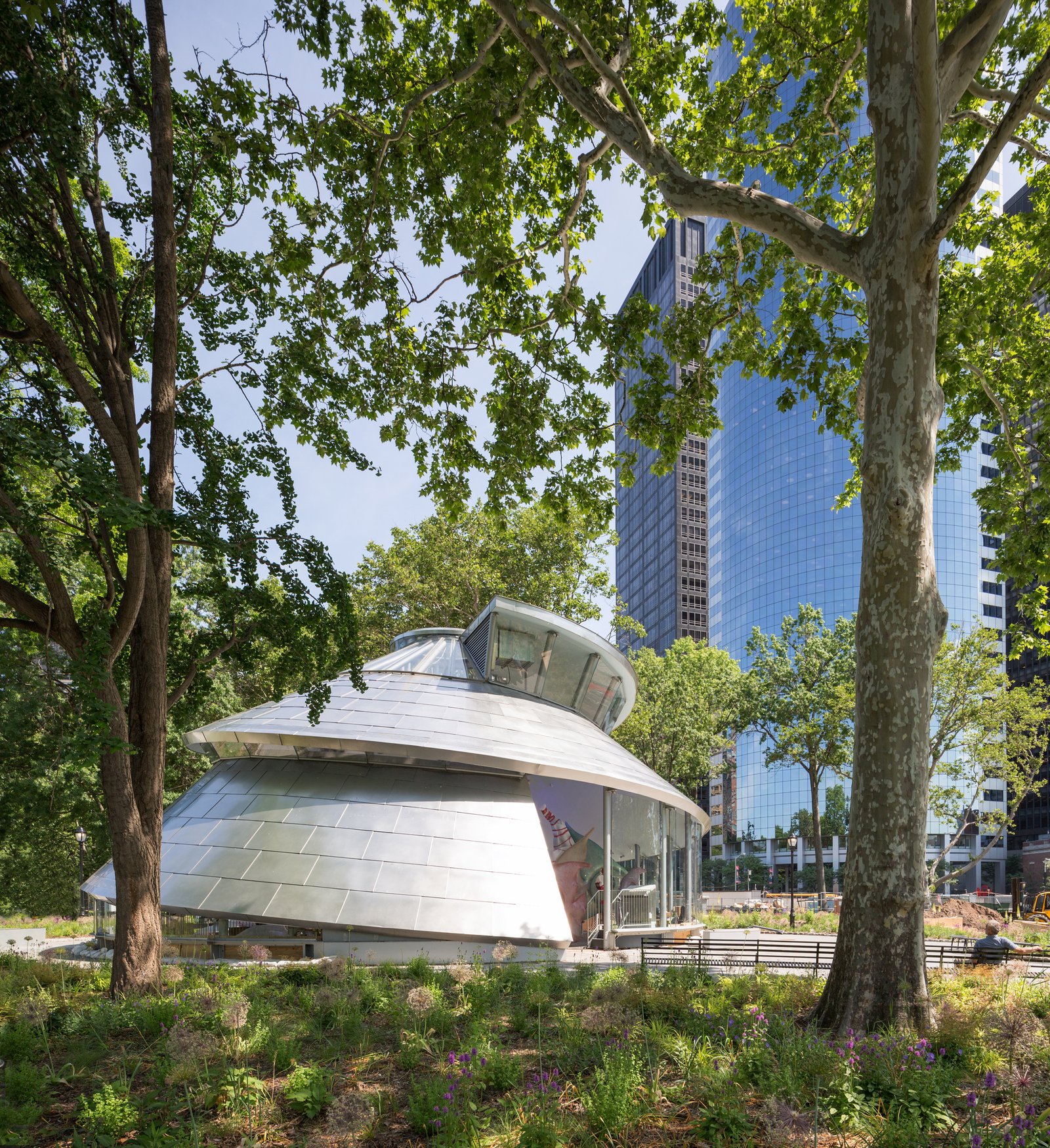 SeaGlass Carousel structure surrounded by trees with a city building in the background.