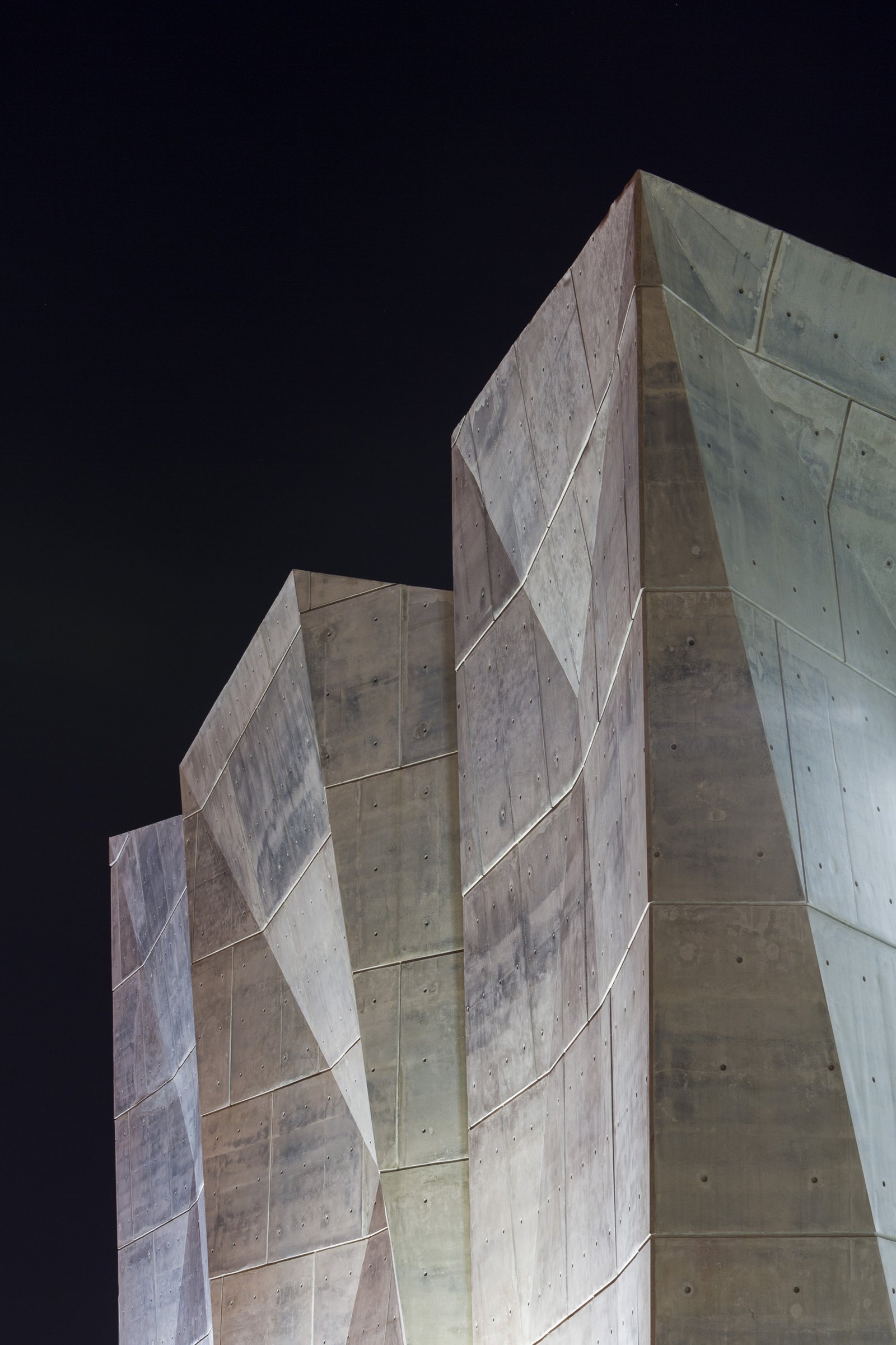 Close-up view of the angular concrete Salt Shed structure at night.