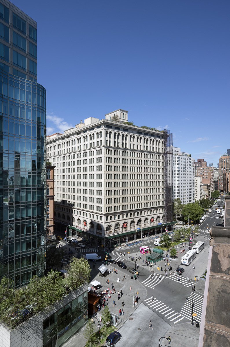 Aerial view of Astor Place intersection with pedestrians, vehicles, and surrounding buildings.