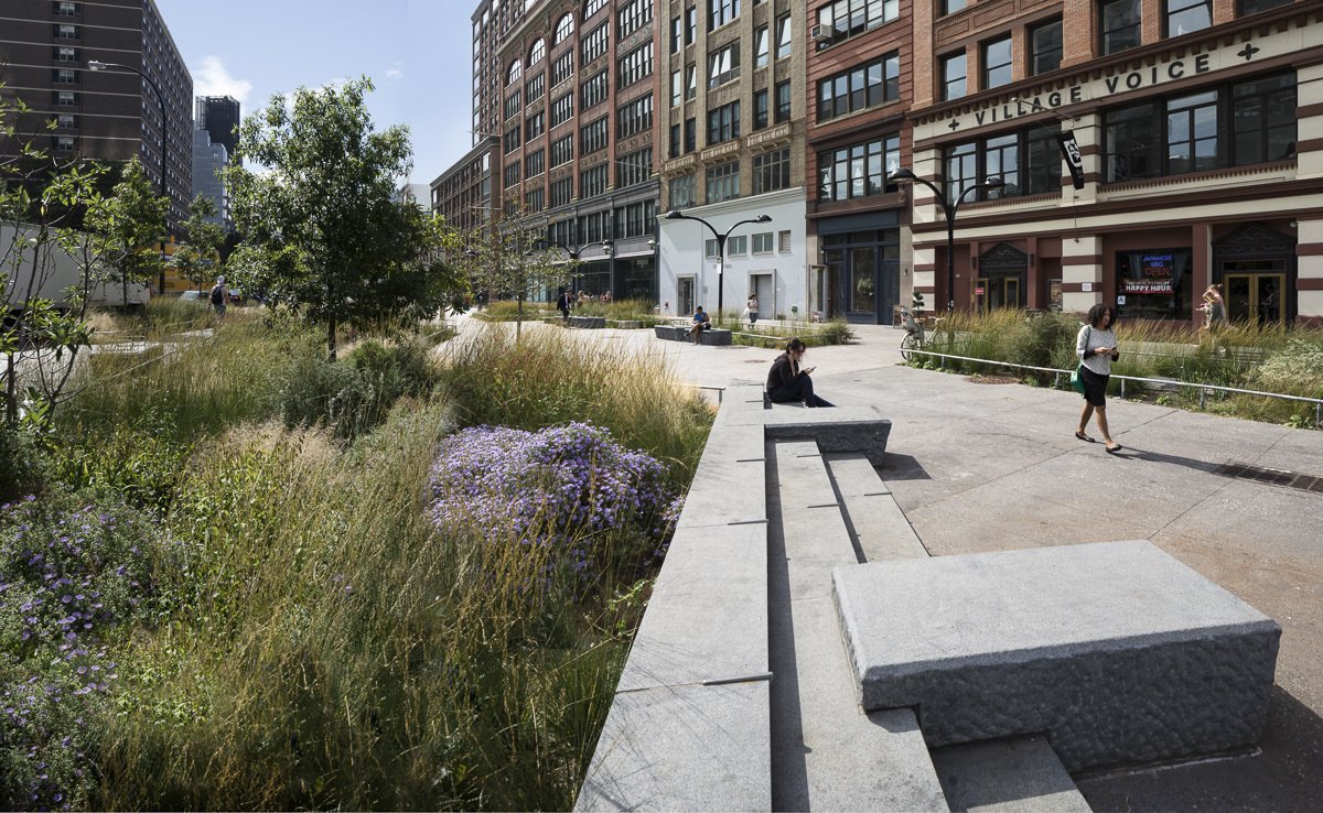 Stone seating and wildflower plantings create a serene plaza with historic buildings in the background.