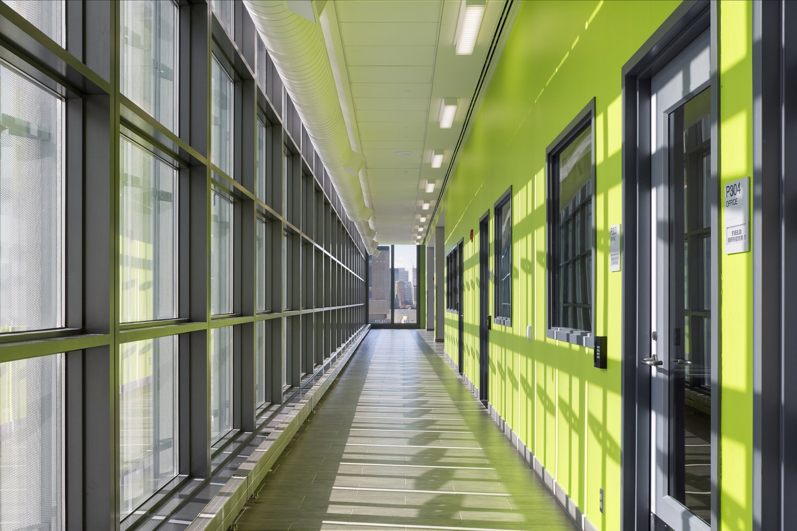 Interior hallway with bright green walls and large windows allowing natural light.