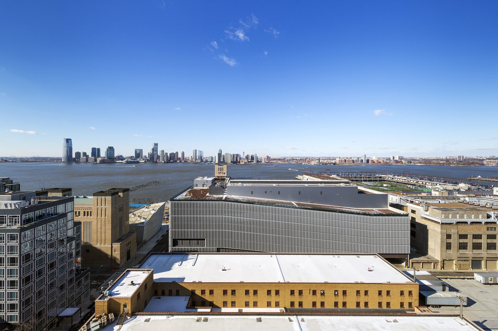 An aerial view of DSNY garage with Hudson River and Jersey City skyline in the background.