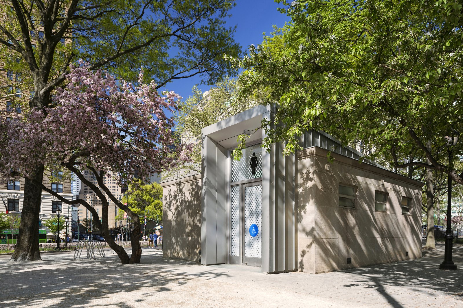 A modernized comfort station with a restored limestone façade surrounded by trees in Battery Park.