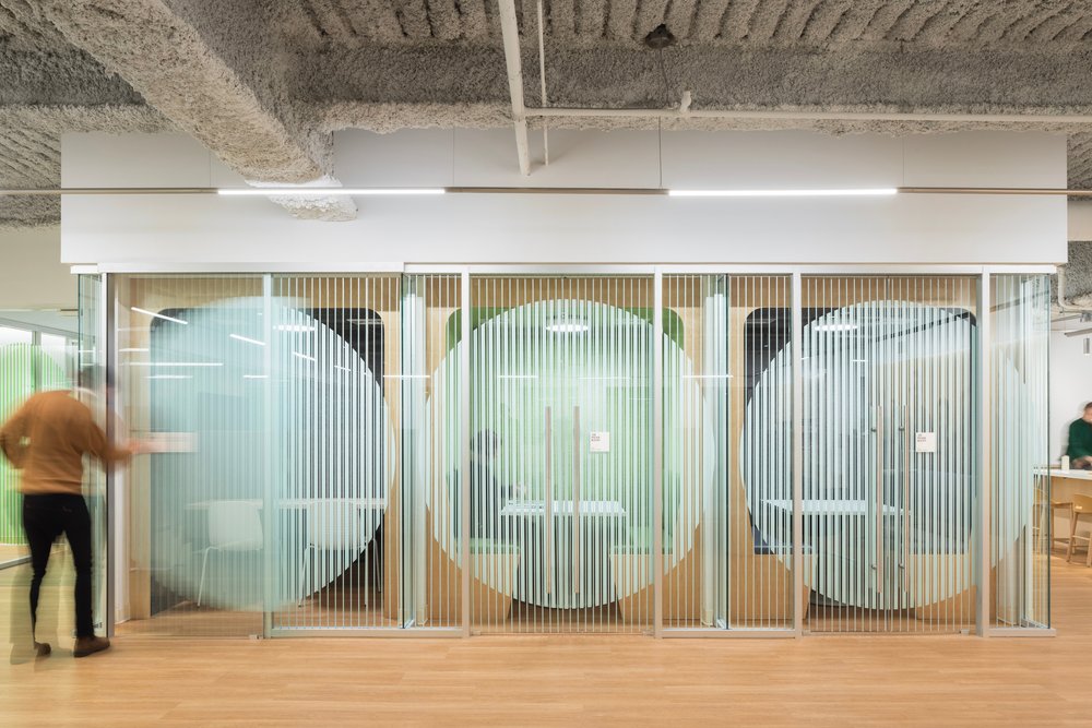 Glass-walled meeting rooms with frosted circle design for privacy.