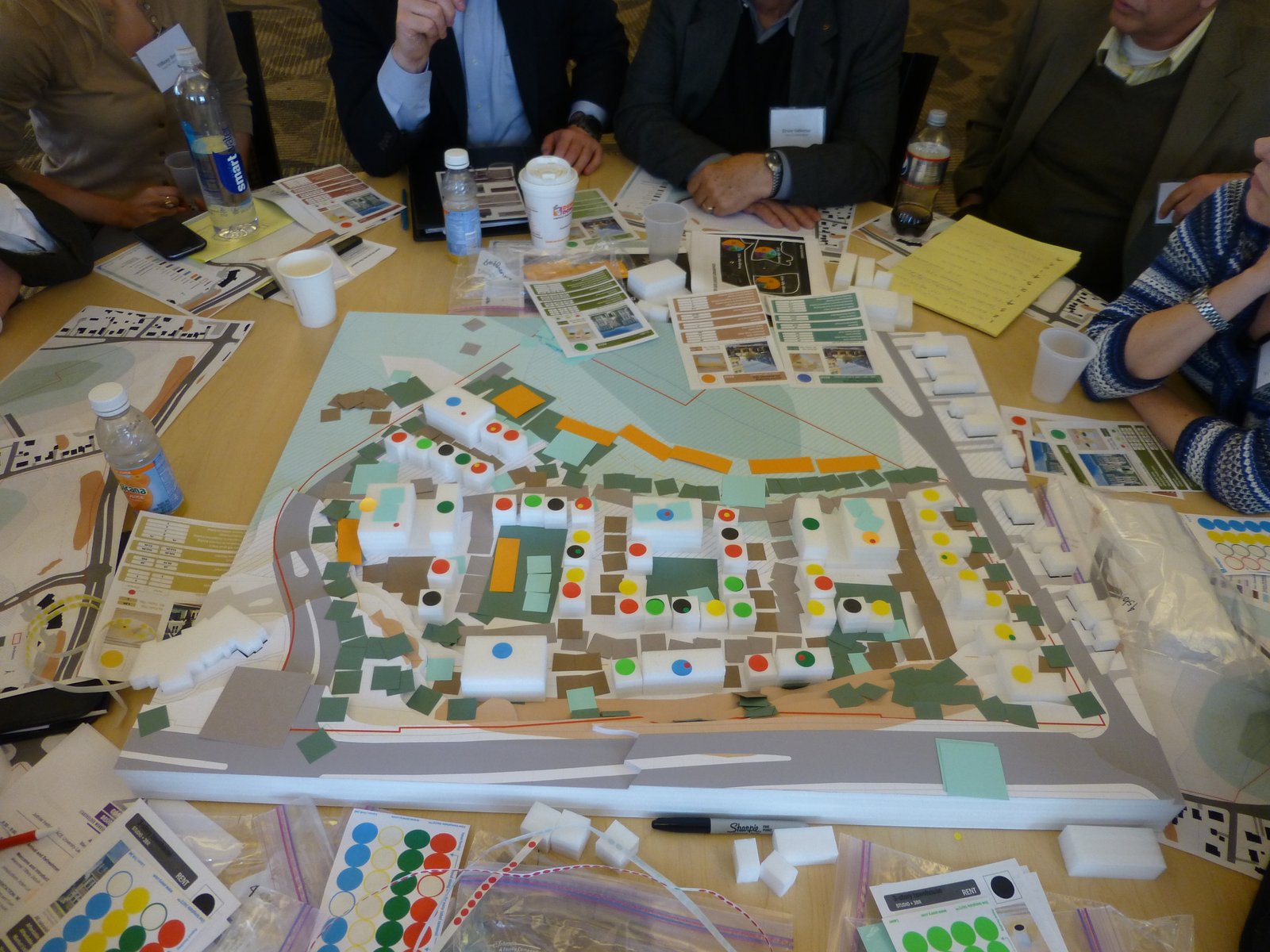 Participants collaborate around a colorful urban planning model during a workshop.