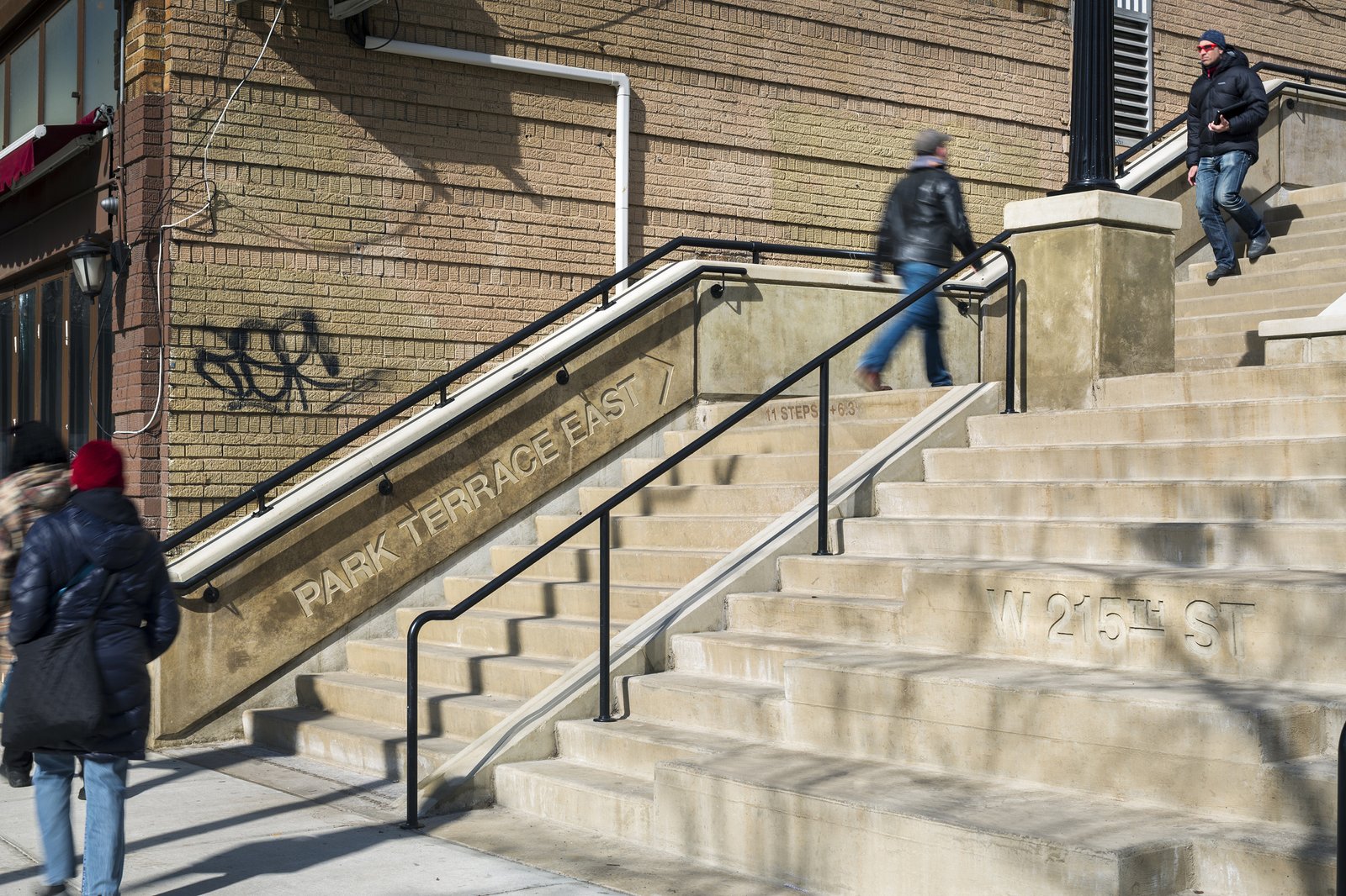 Close-up of the West 215th Step Street with engraved street names and modern handrails.