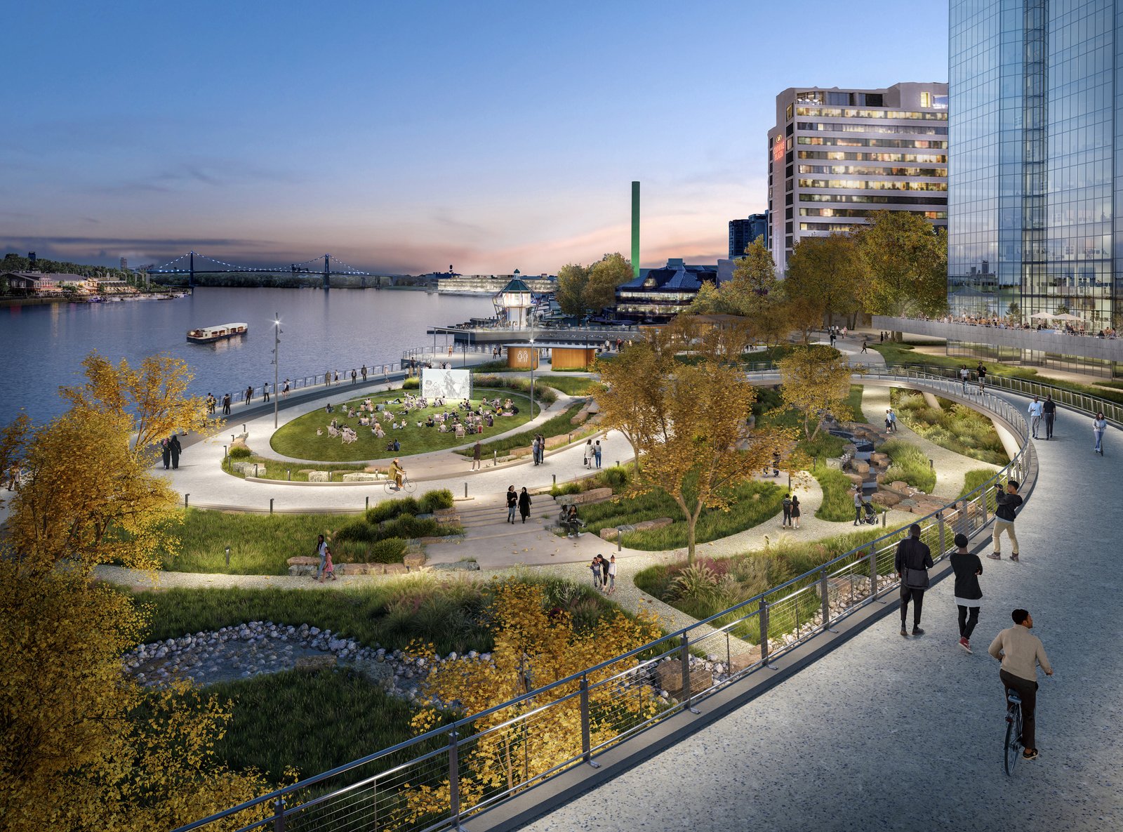 Elevated view of an urban riverfront park with a lawn, paths, and waterfront promenade.