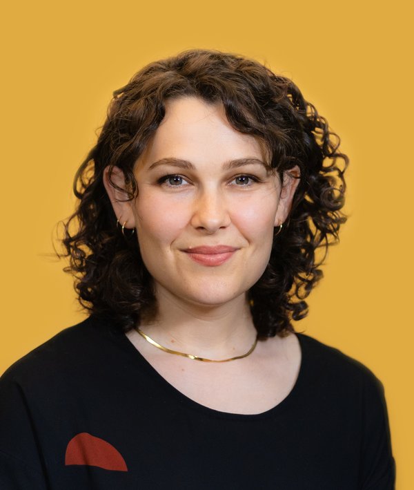 Headshot of Abby Zan in a dark top against a yellow background.