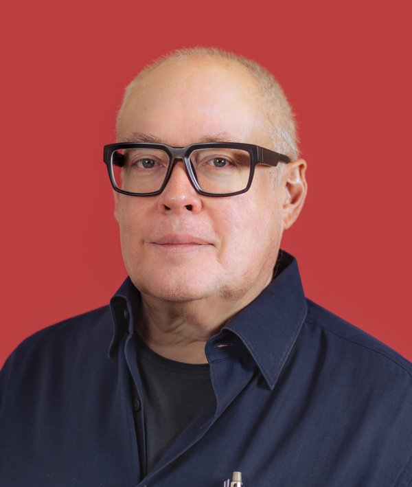 Headshot of Mark Yoes with a dark shirt and red background.