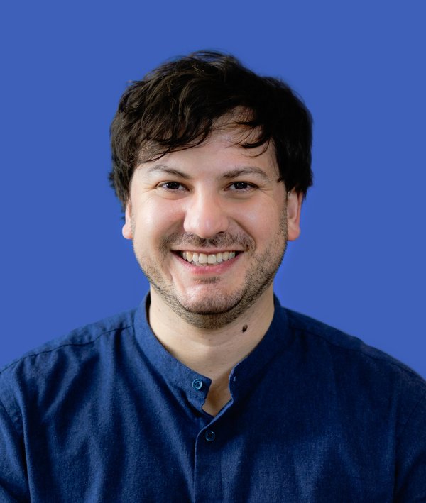 Headshot of Robert Daurio in a blue shirt against a blue background.