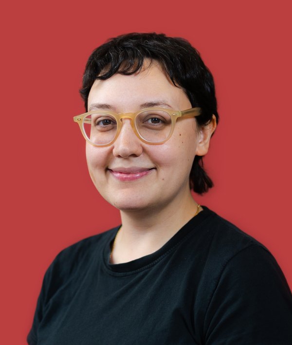 Headshot of Sarah Yoes in a black top against a red background.