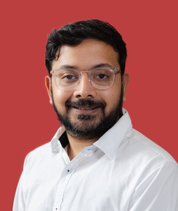 Headshot of Govardan Rajasekaran Umashankar in a white shirt against a red background.