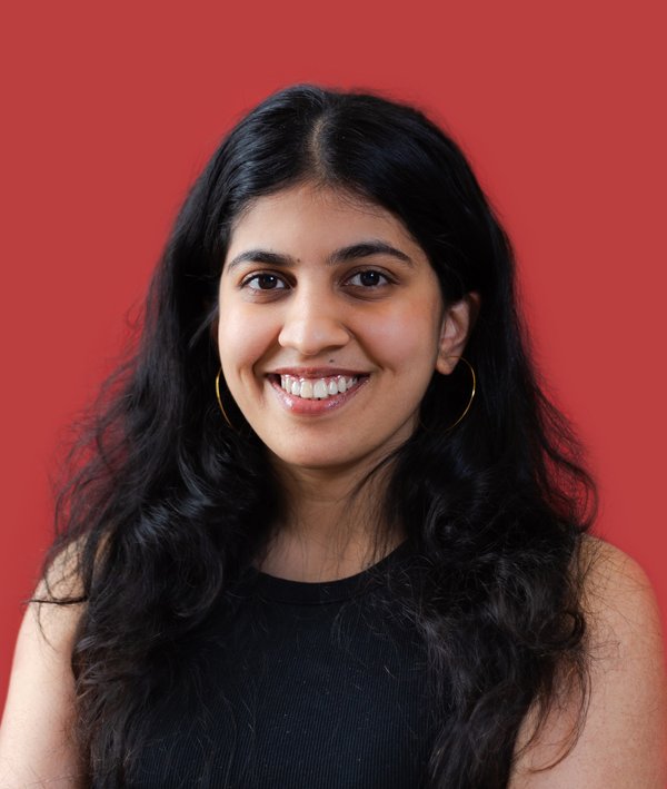 Headshot of Aakanksha Jain in a dark top against a red background.