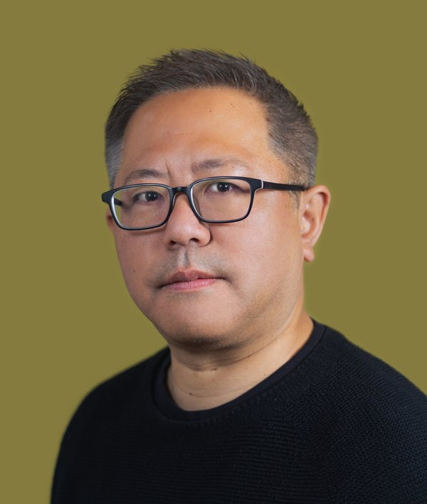 Headshot of Nobuhiko Arai in dark shirt against a green background.