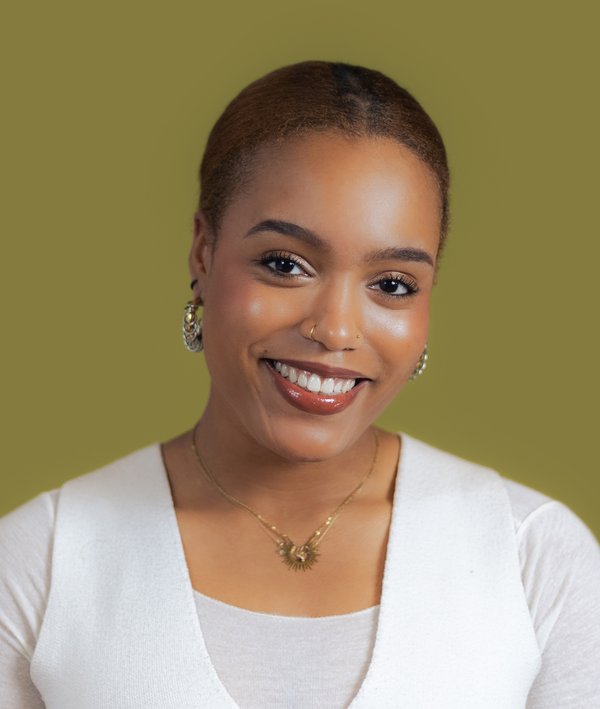 Headshot of Maïra Gomis in a white top against a green background.