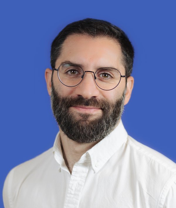 Headshot of Majed Abdulsamad in a white shirt against a blue background.