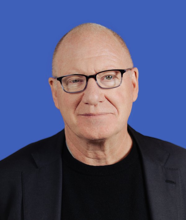 Headshot of Robert Young with a grey blazer against a blue background.