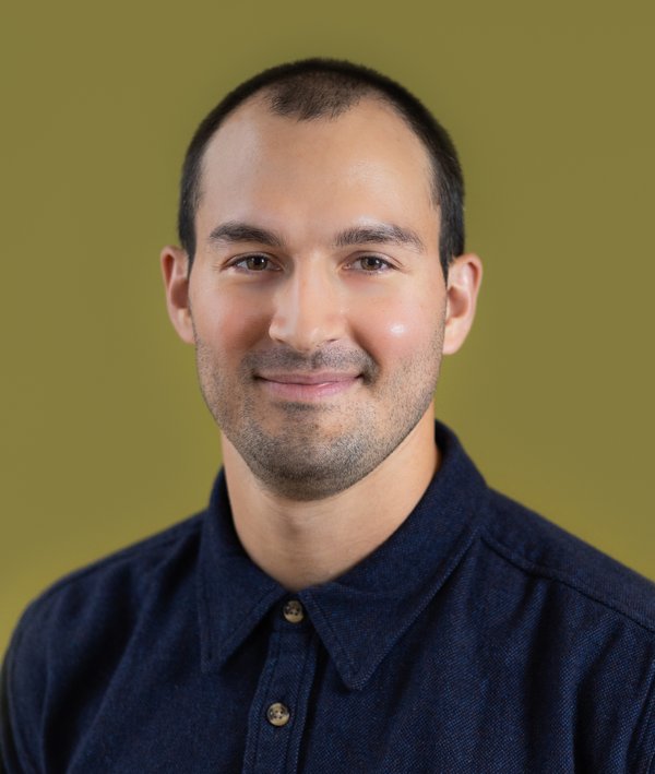 Headshot of Mario Giampieri in a dark shirt against a green background.