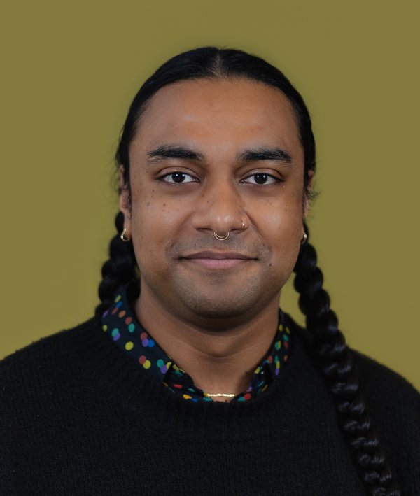 Headshot of Ien Boodan in a black shirt against a green background.