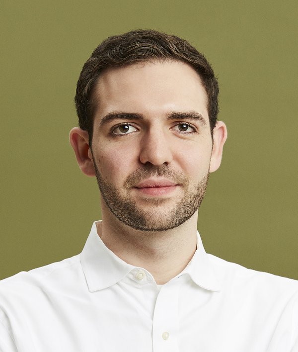 Headshot of Asher Intebi in a white shirt against a green background.