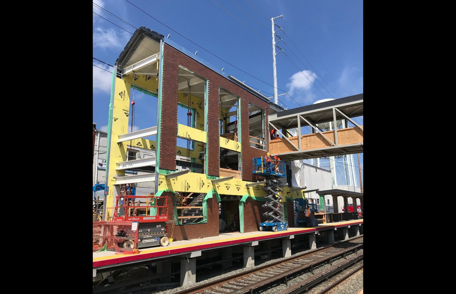 Station building under construction with exposed steel and brick facade elements.