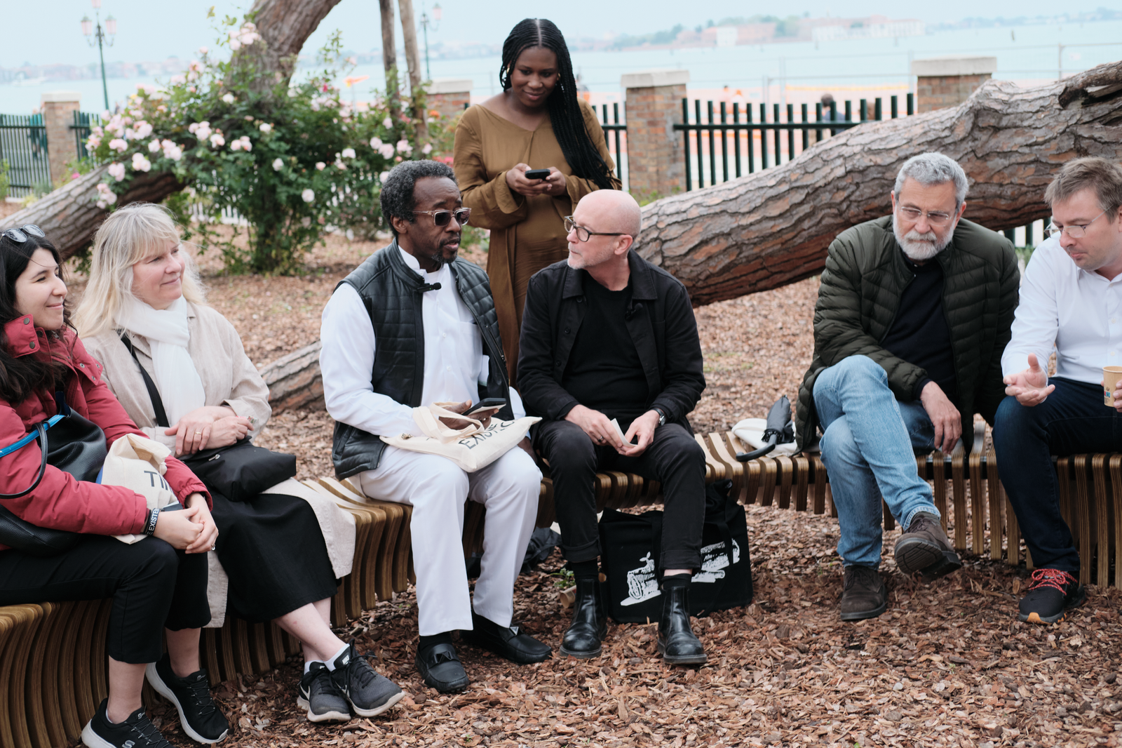 A group of people sitting on a curved bench having a conversation.