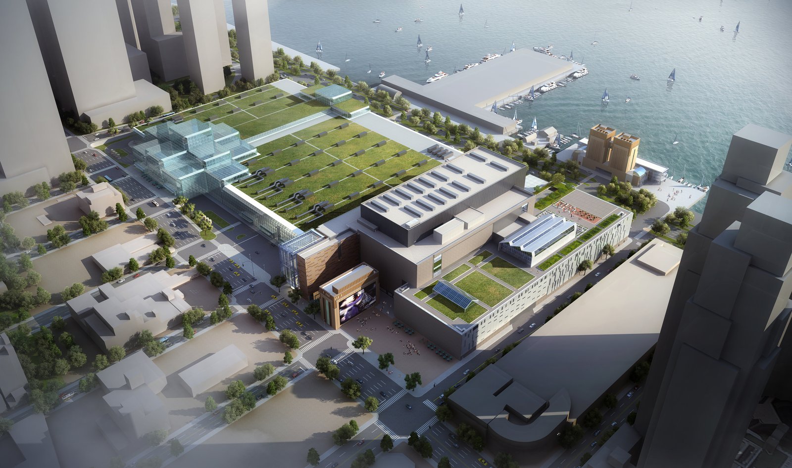 An aerial view shows a building complex with green rooftops and glass structures, located next to a waterfront with boats.