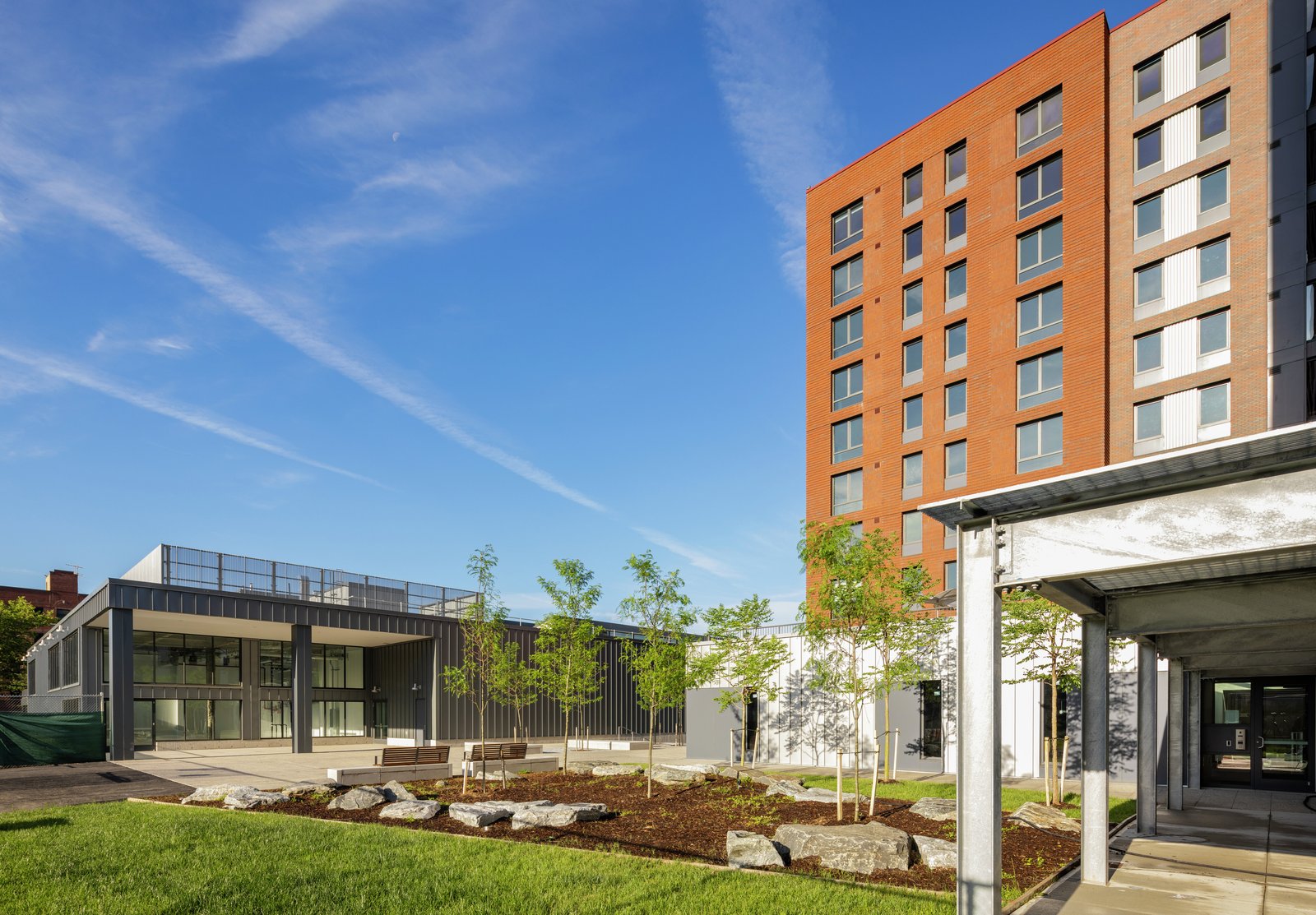 Modern building with a landscaped courtyard featuring rocks, trees, and greenery.