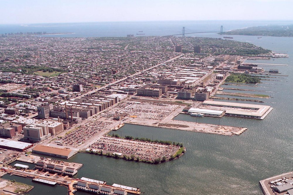 Aerial view of industrial waterfront complex and surrounding urban area.