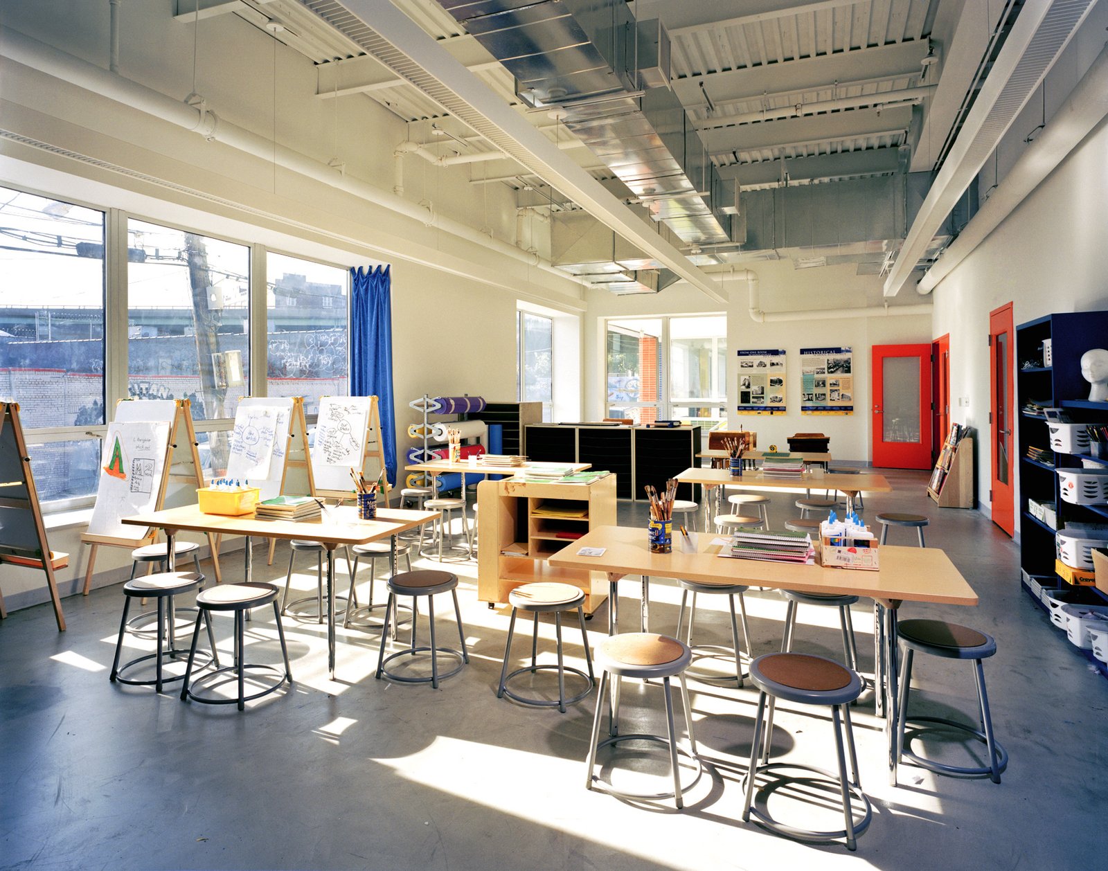 Bright classroom with stools, tables, and large windows in a modern learning space.