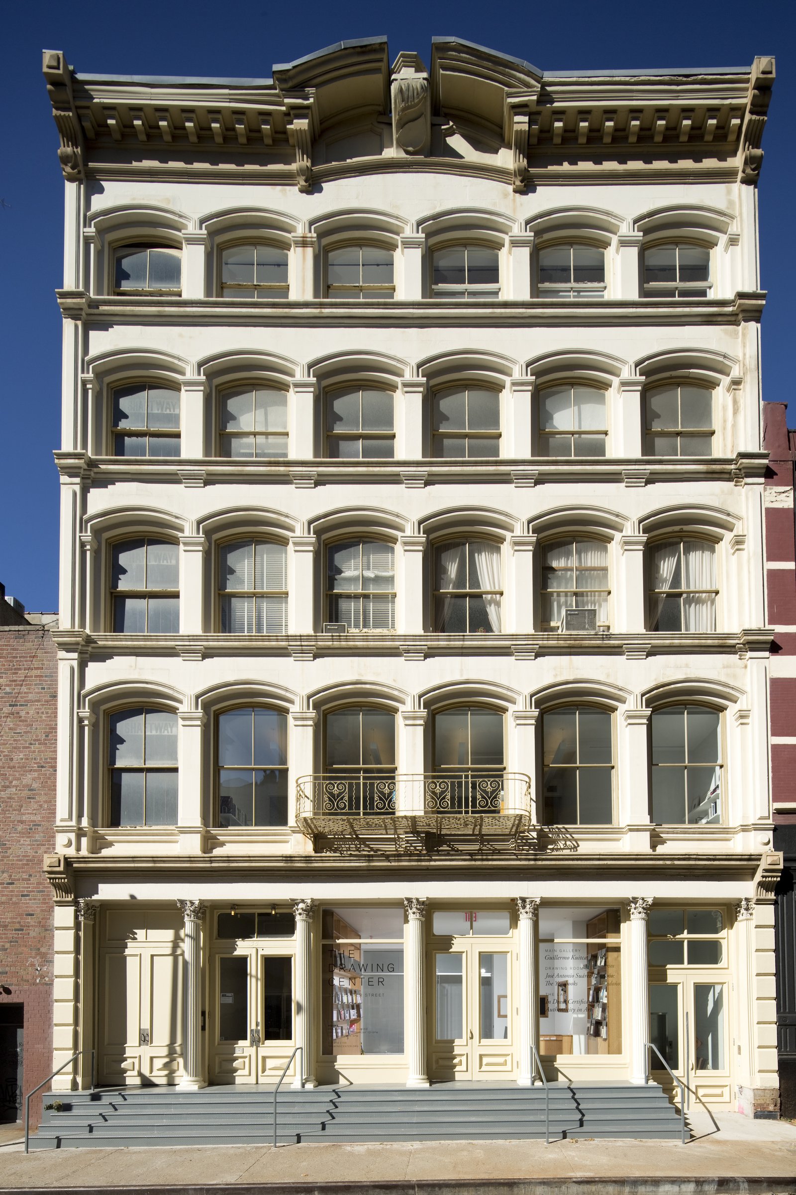 Five-story cast-iron building with repeating arched windows, ornate cornice, and decorative iron balcony.