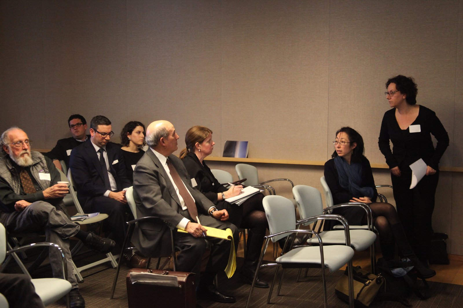 People seated and engaged in a discussion at a conference room meeting.