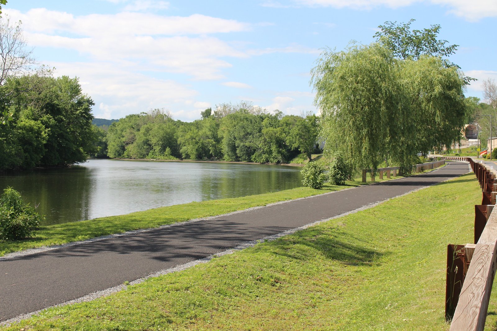 Paved pathway along the Housatonic River with lush greenery.