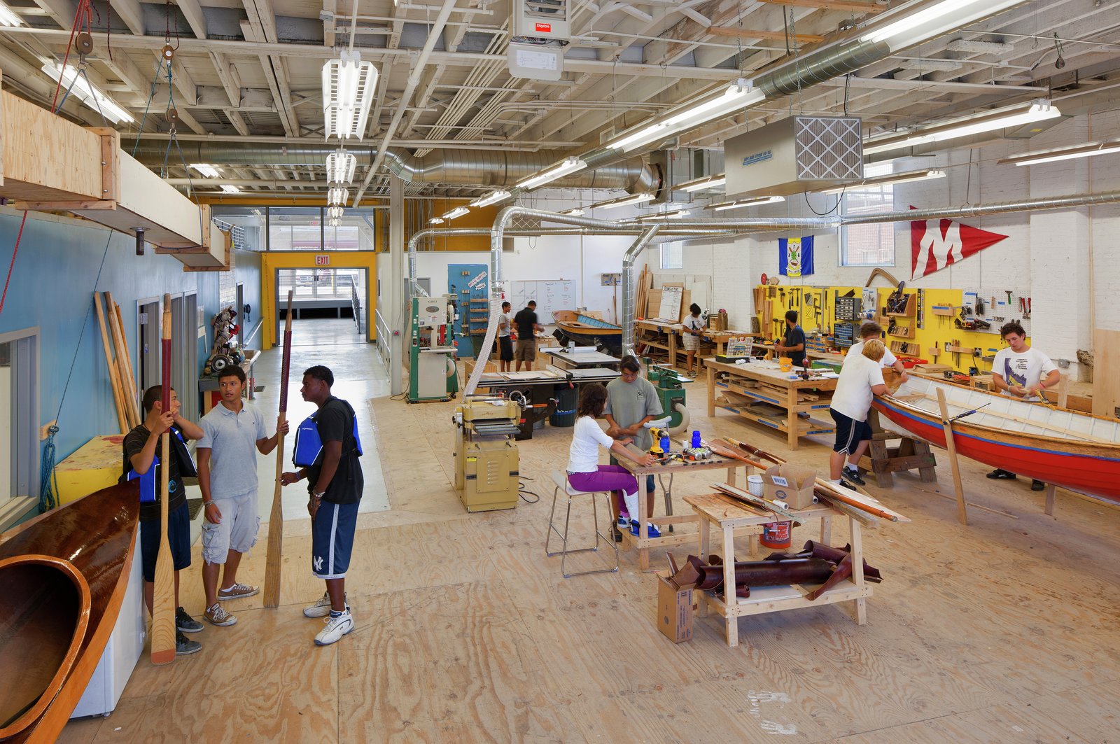 Open workshop with people building boats in a bright, spacious setting.