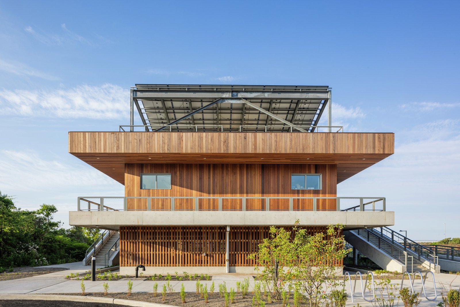 Front view of the Coastal Conservation Center featuring vertical wood siding, a wraparound porch, and rooftop solar panels.