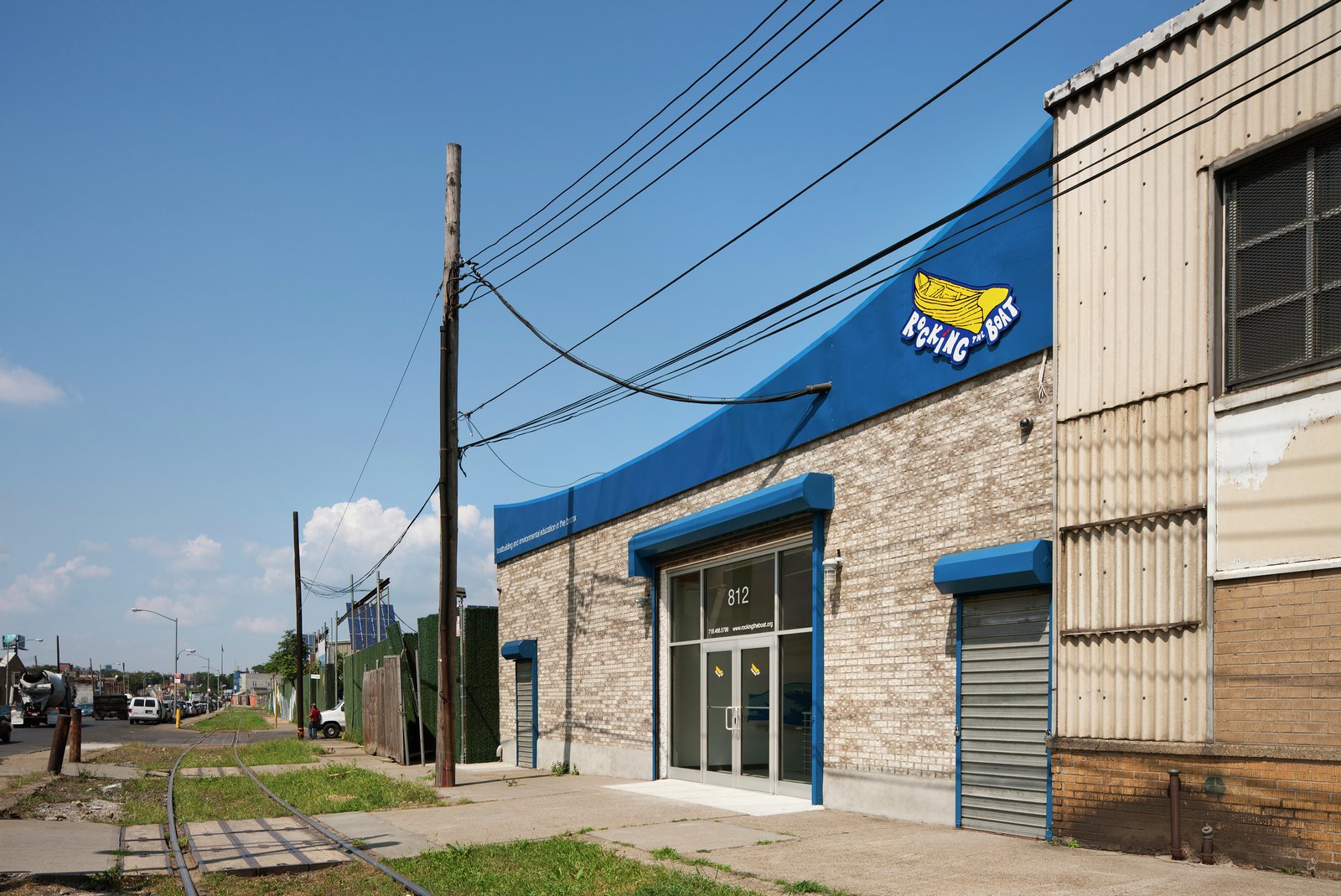 Brick building with blue awning in an industrial neighborhood, featuring a glass entry.