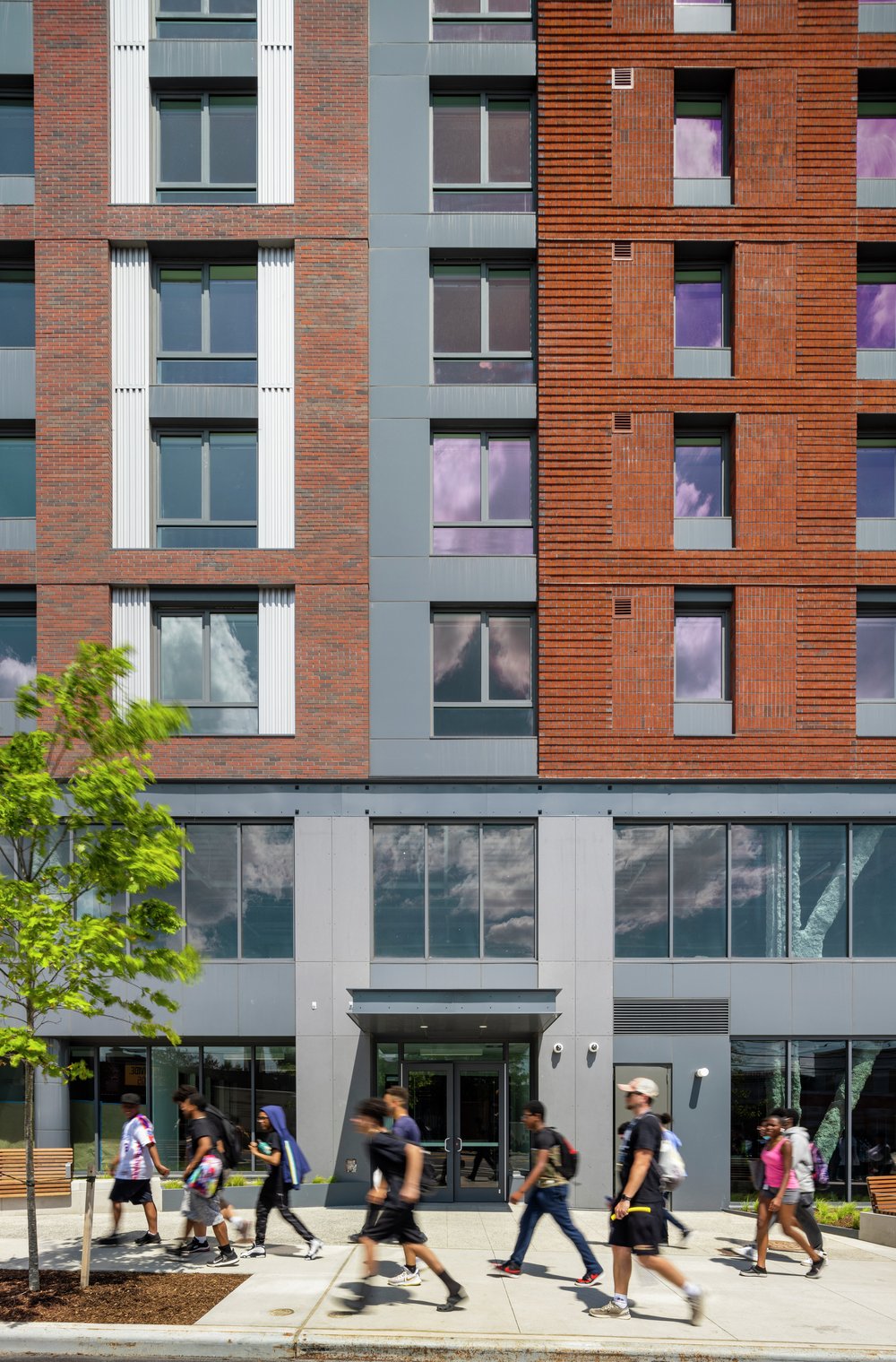 Pedestrians walk in front of the residential building at The Peninsula in Hunts Point.