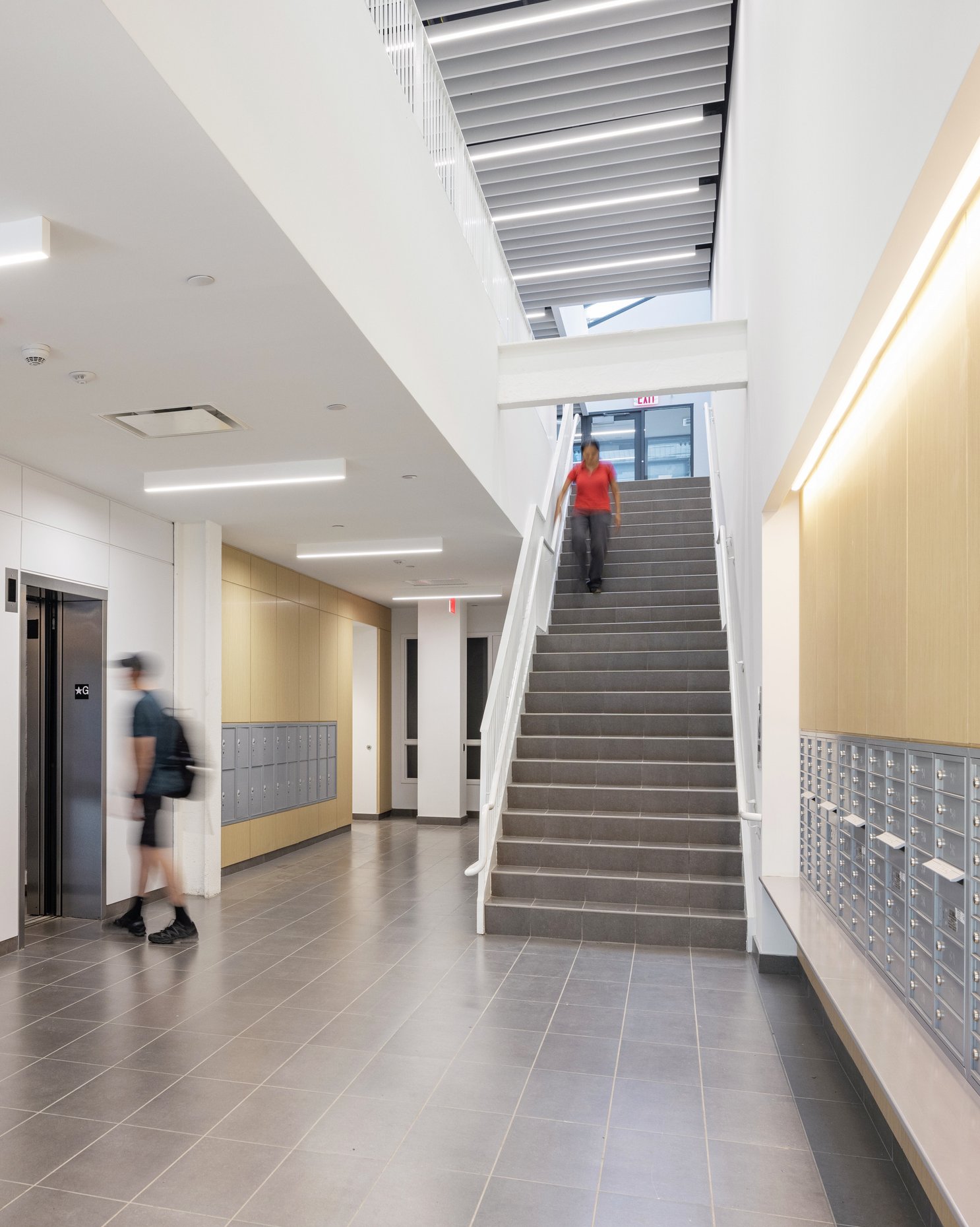 Lobby with elevators, mailboxes, and a stairway leading to upper floors.