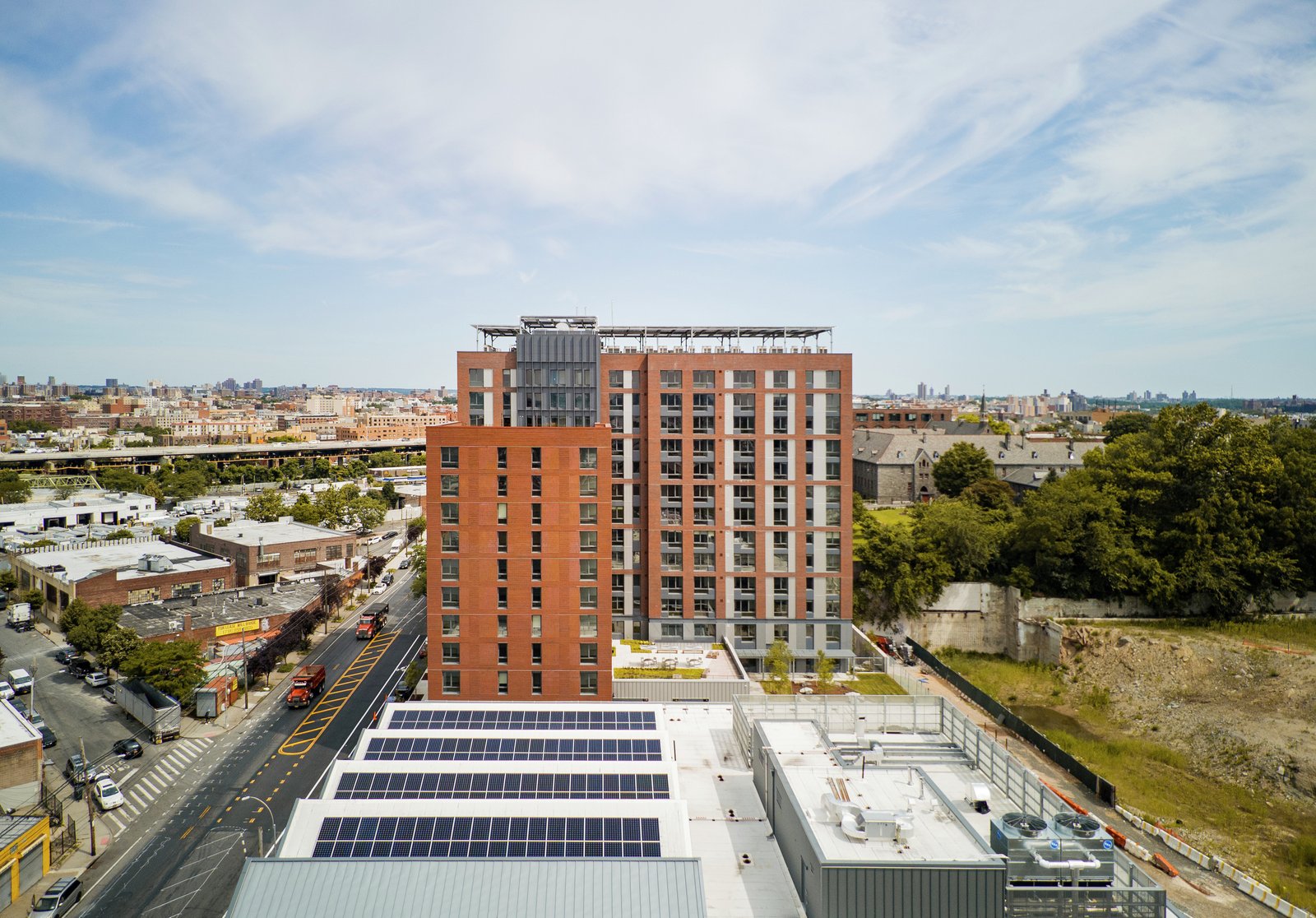 Aerial view of mixed-use development with red brick residential tower.