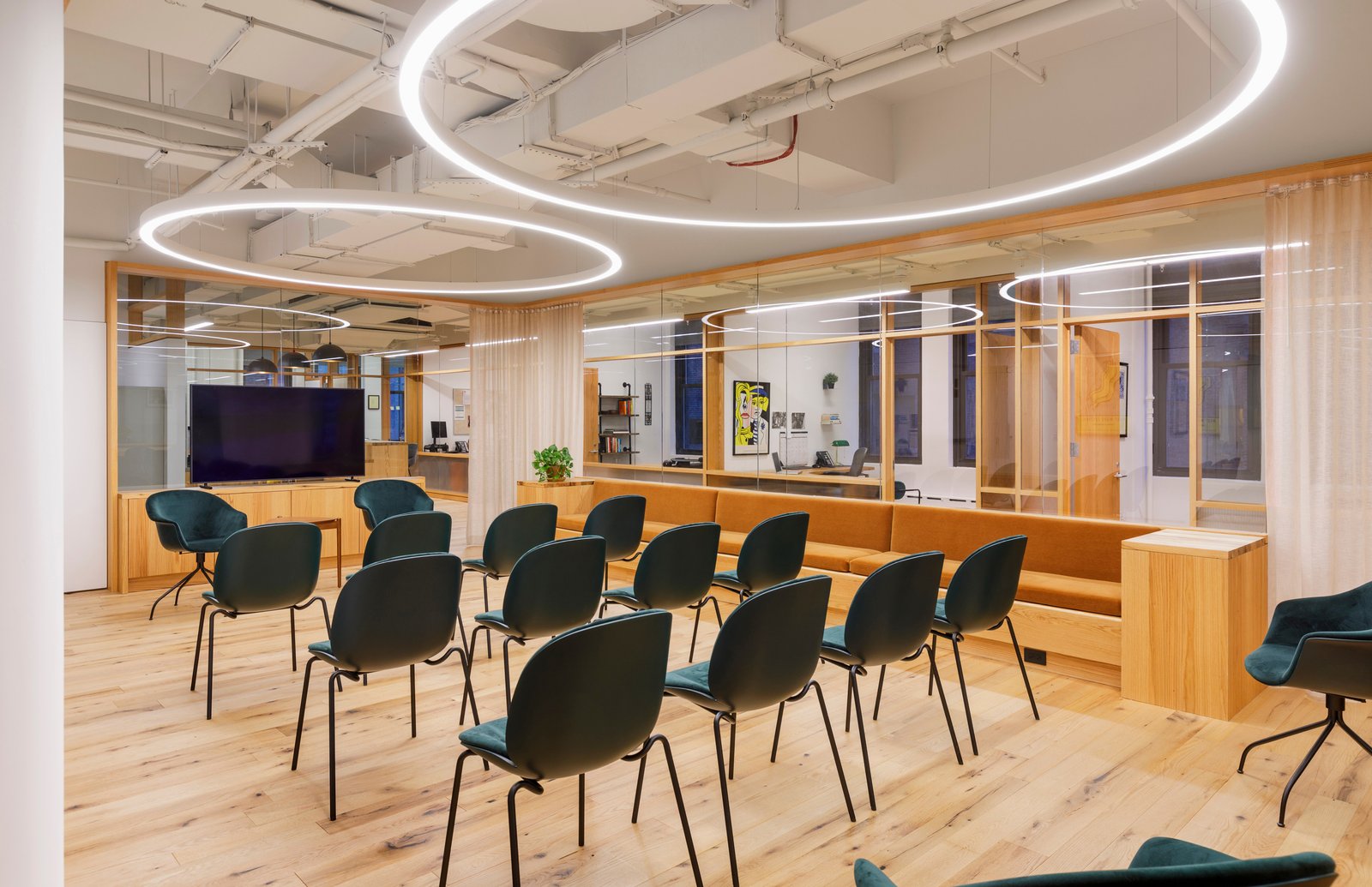 Flexible seating area with wood accents, glass partitions, and circular lighting.