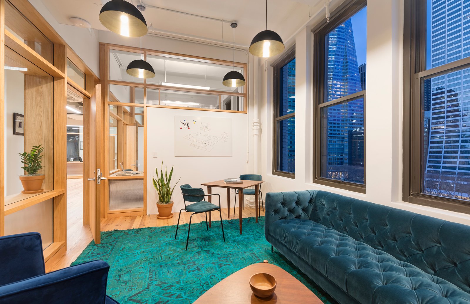 Intimate meeting space with velvet seating, pendant lights, and city views.