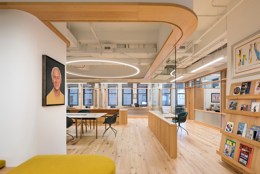 Office with wood accents, curved glass partitions, and a portrait.