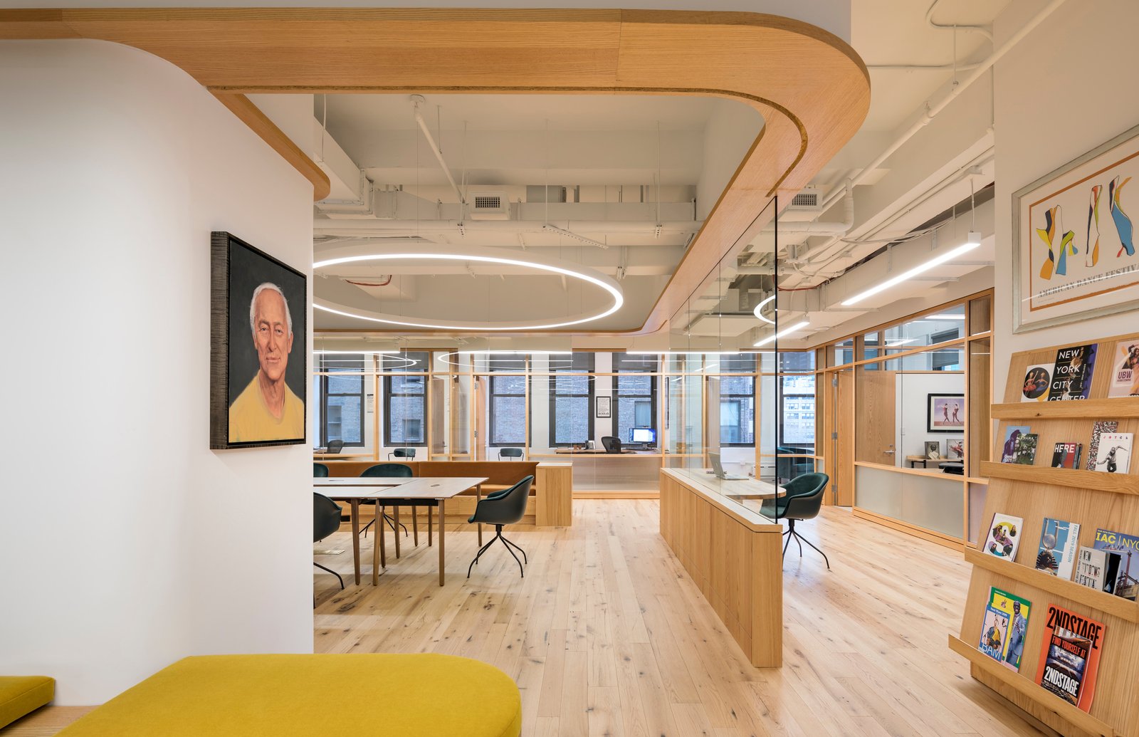 Office with wood accents, curved glass partitions, and a portrait.