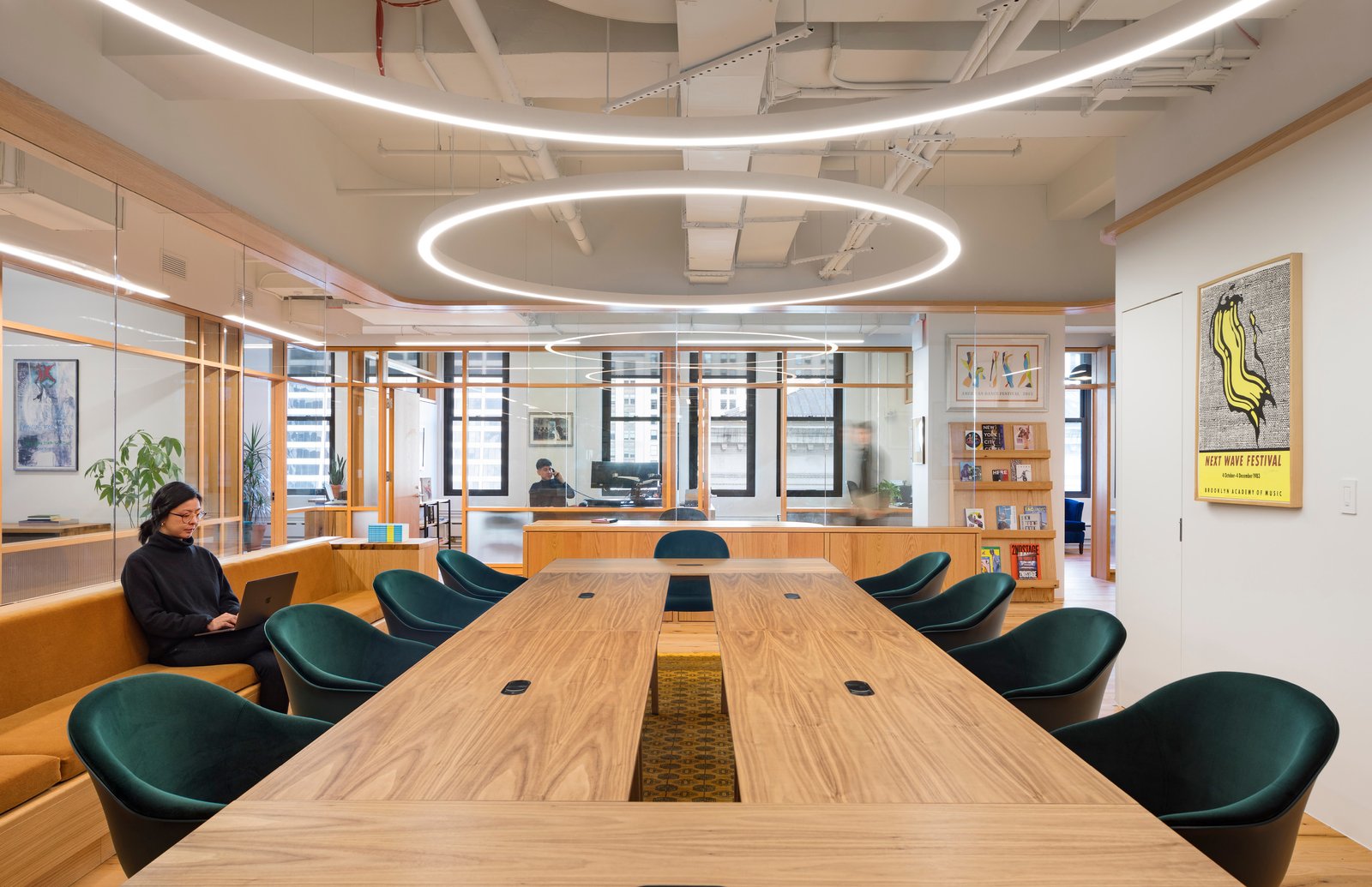 Conference room with wood table, green chairs, and circular light fixtures.