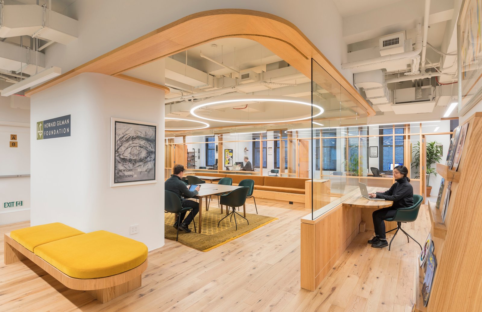 Open workspace with curved wood details, glass partitions, and circular lighting.