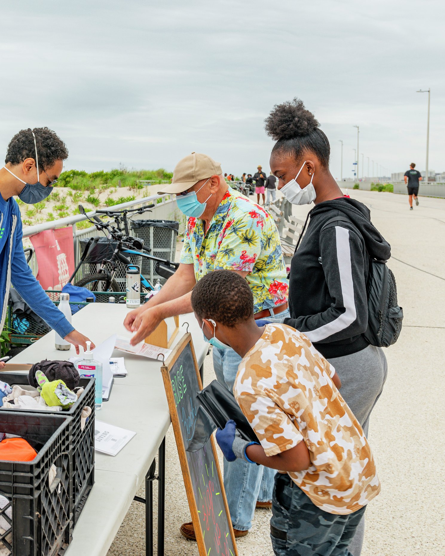 Volunteers and community members gather at a table with supplies for a dune restoration event.